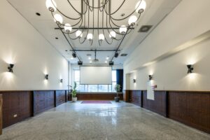 Vergaderruimte aan de Johan Huizingalaan met grote kroonluchter, projectiescherm en moderne wandverlichting.
